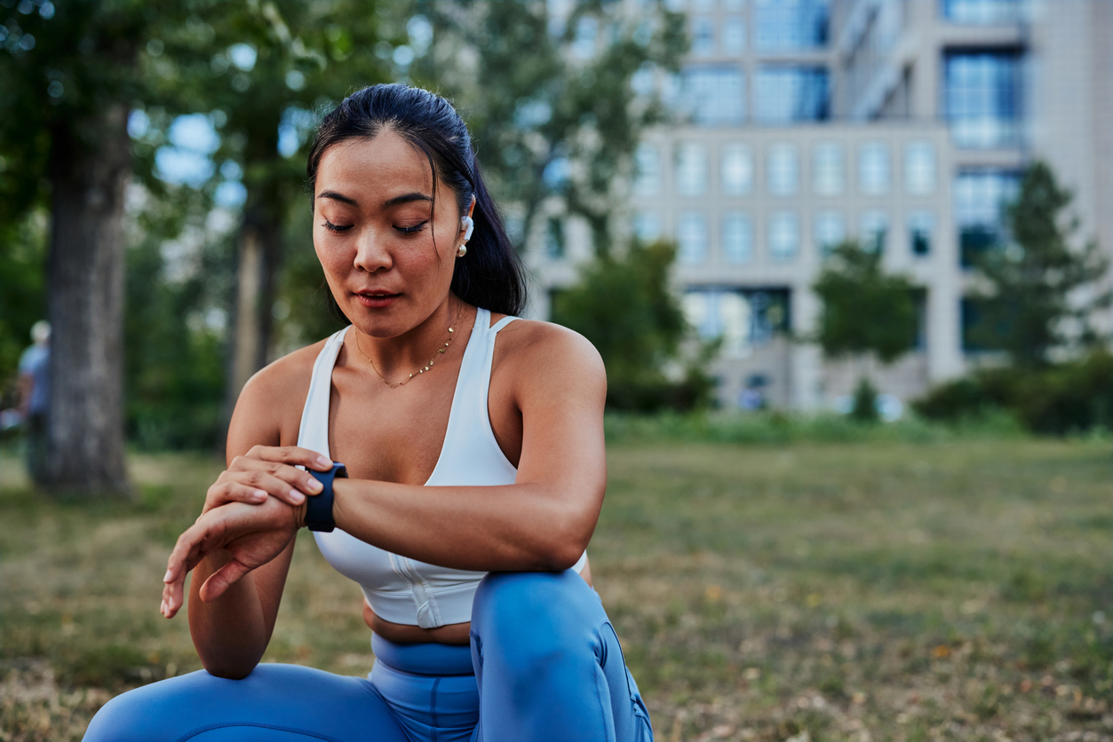 Woman looking at watch during workout outdoors.