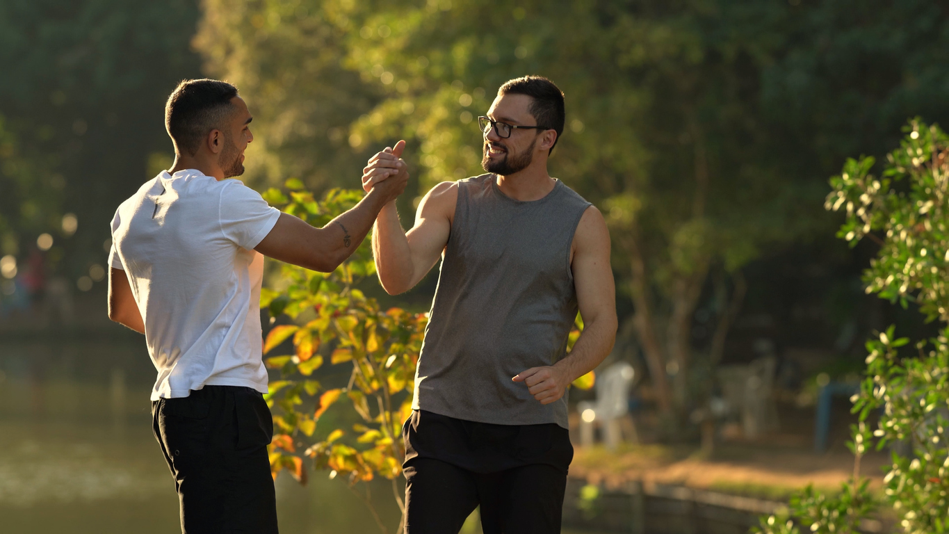 Two men talking outside while exercising. 