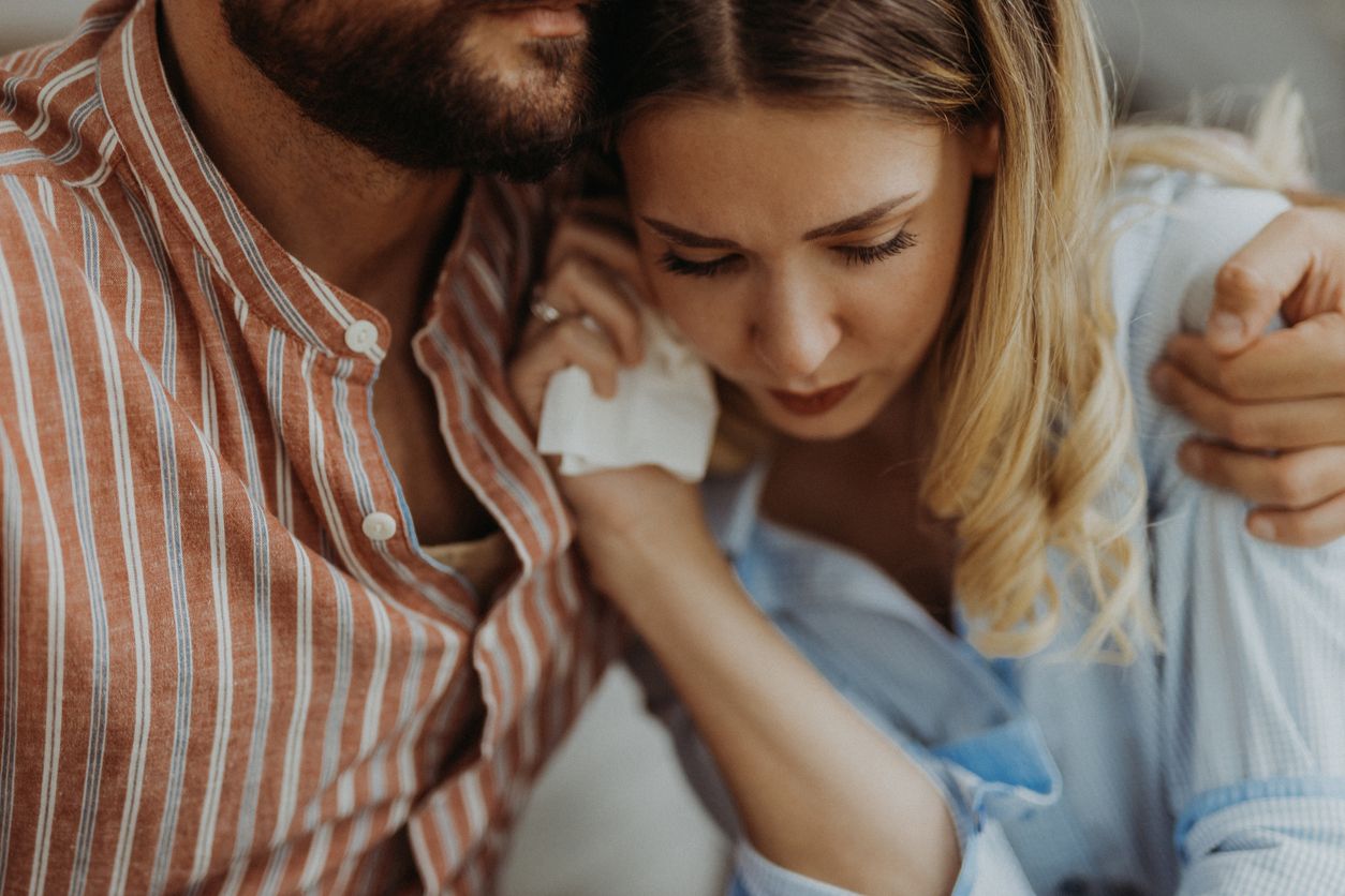 Woman crying and being consoled by a man.