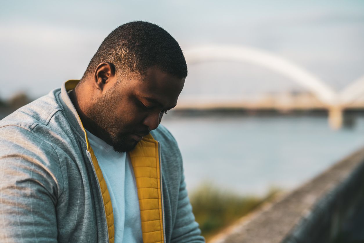 Man sitting outside feeling depressed.