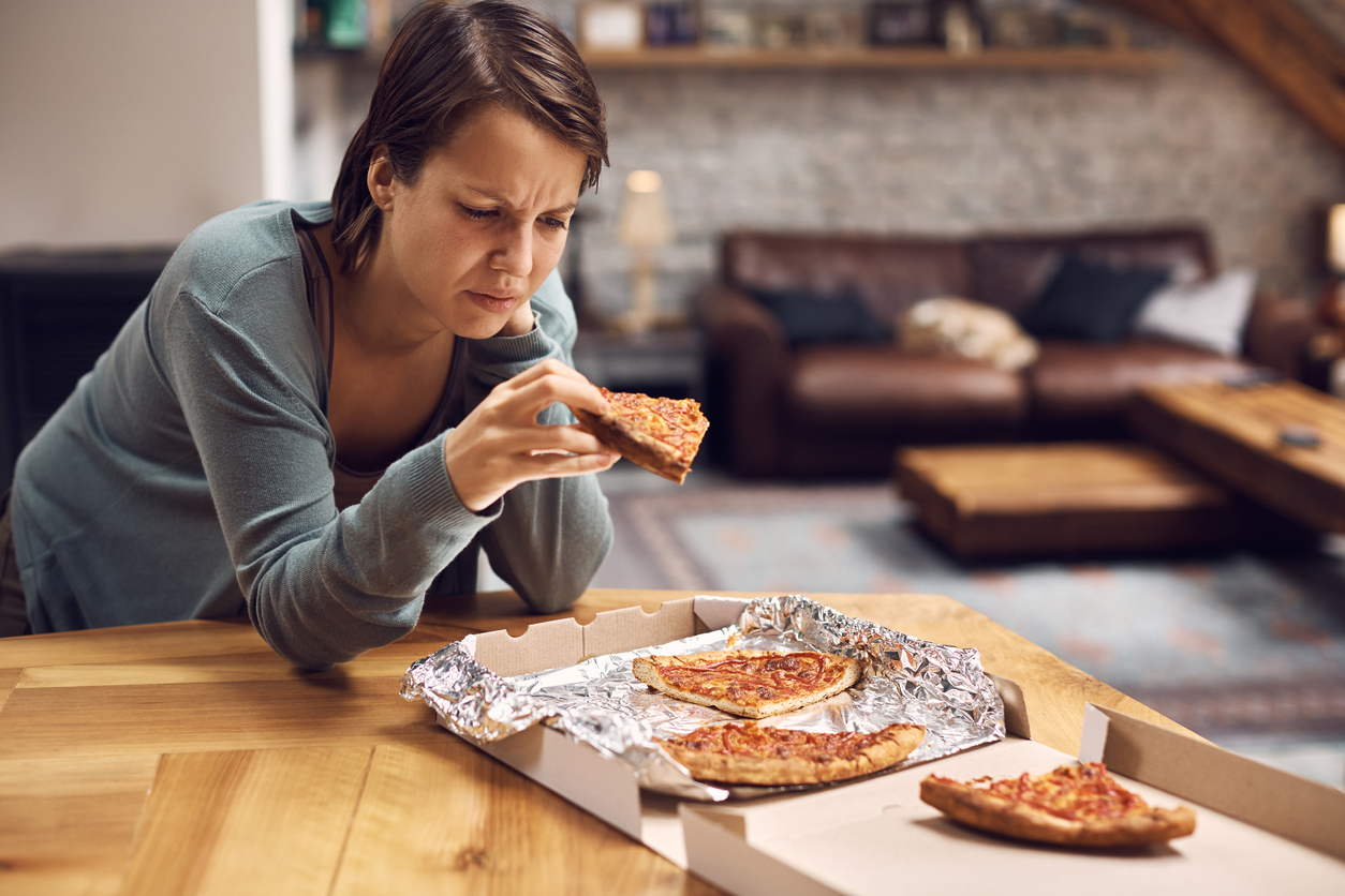 Woman looking sad and holding pizza.