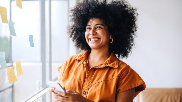 Happy black businesswoman smiling while using a smartphone