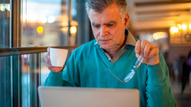 older man reading news on his computer