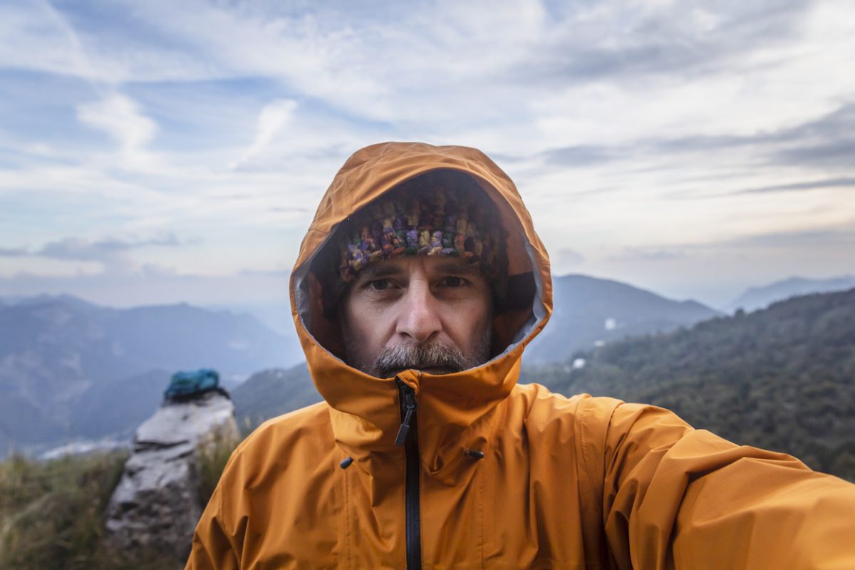 Mature man with rain jacket in the mountains looking at camera