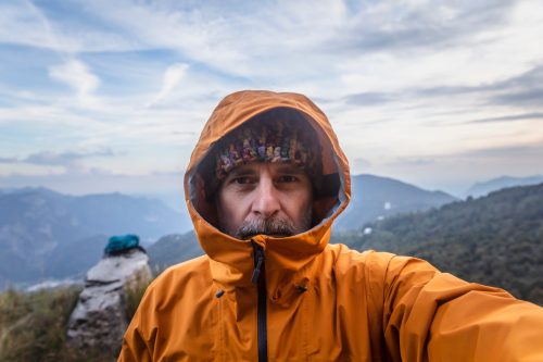 Mature man with rain jacket in the mountains looking at camera