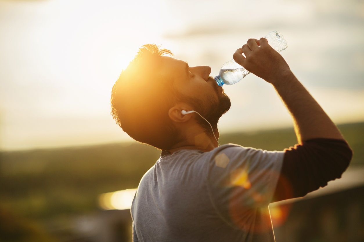 Man drinking water outdoors.