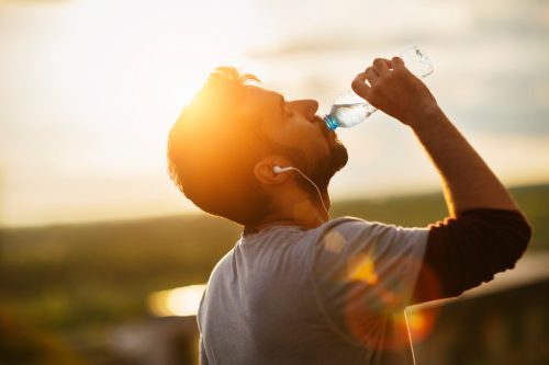 Man drinking water outdoors.