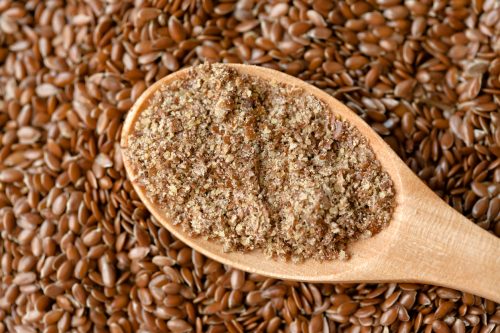Flaxseeds and ground flaxseed in a spoon.