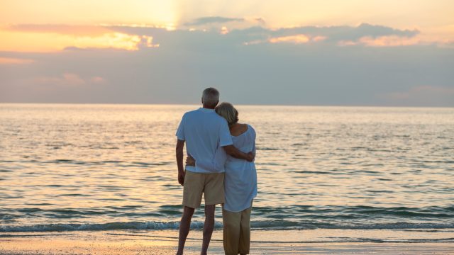 Mature couple at sunset or sunrise on the beach.