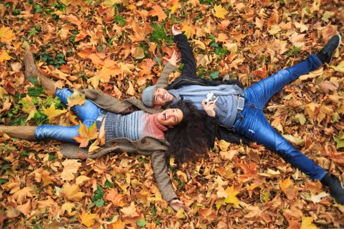 Smiling couple lying down in leaves.