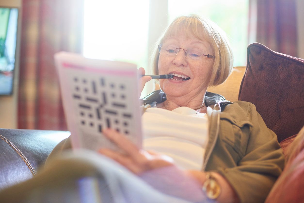 Senior woman doing crossword puzzle at home.