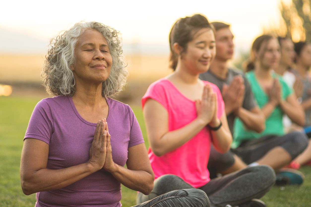 Women doing yoga and meditation outdoors.