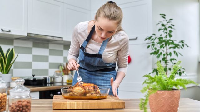 Woman cooking baked chicken at home in the kitchen. Homemade food, traditional food for the holidays, delicious eat at home concept