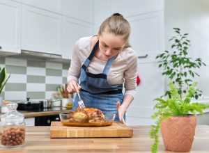 Woman cooking baked chicken at home in the kitchen. Homemade food, traditional food for the holidays, delicious eat at home concept