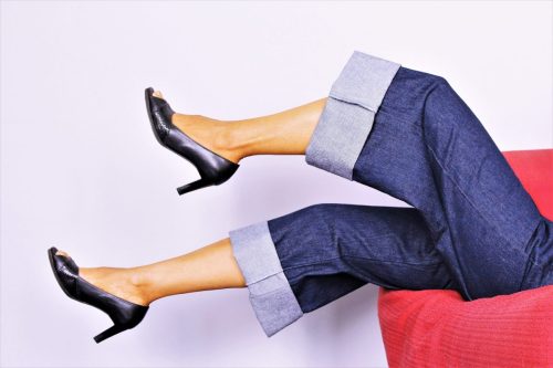 woman legs up in the air wearing wide leg jeans and heels
