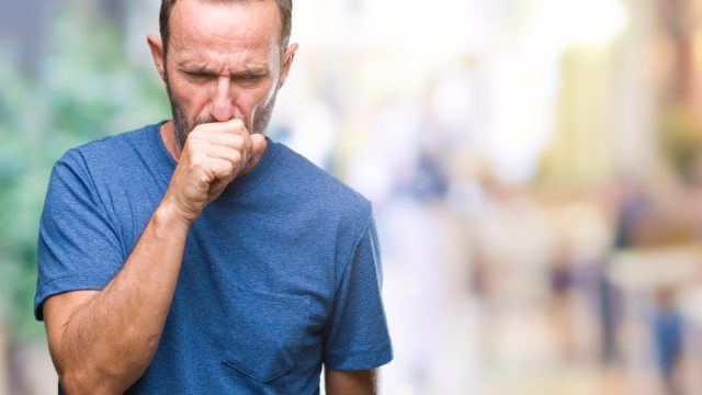 Middle aged man coughing outside