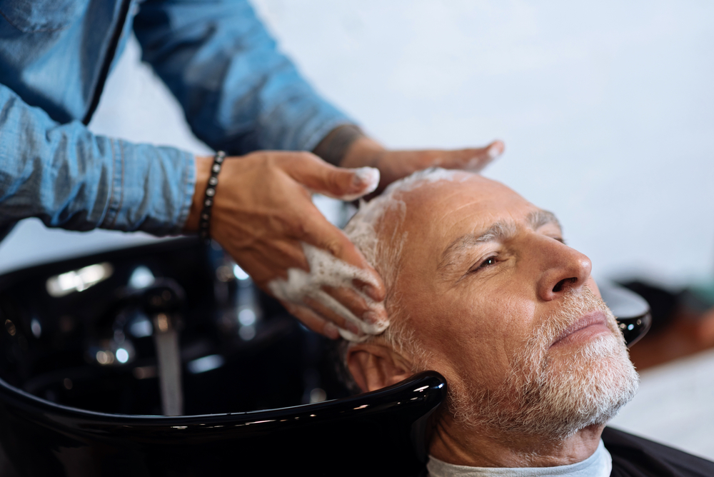 A senior man having his hair washed in a salon