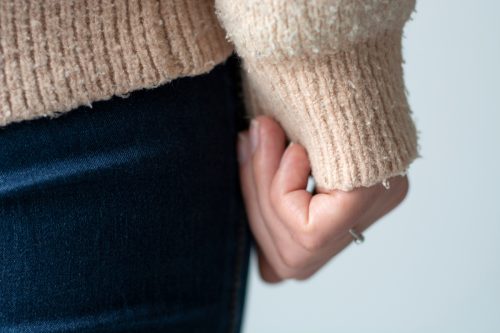 Close up of a woman's hand and arm wearing a pilled sweater.
