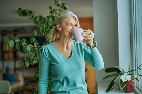 Older woman in aqua sweater drinking coffee