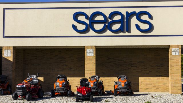 The exterior of a Sears store with ride-on lawnmowers on display
