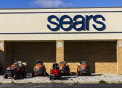 The exterior of a Sears store with ride-on lawnmowers on display