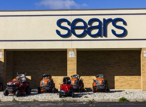 The exterior of a Sears store with ride-on lawnmowers on display