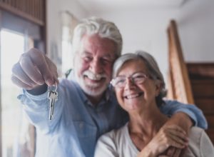 A senior couple hugging while holding keys to a new home