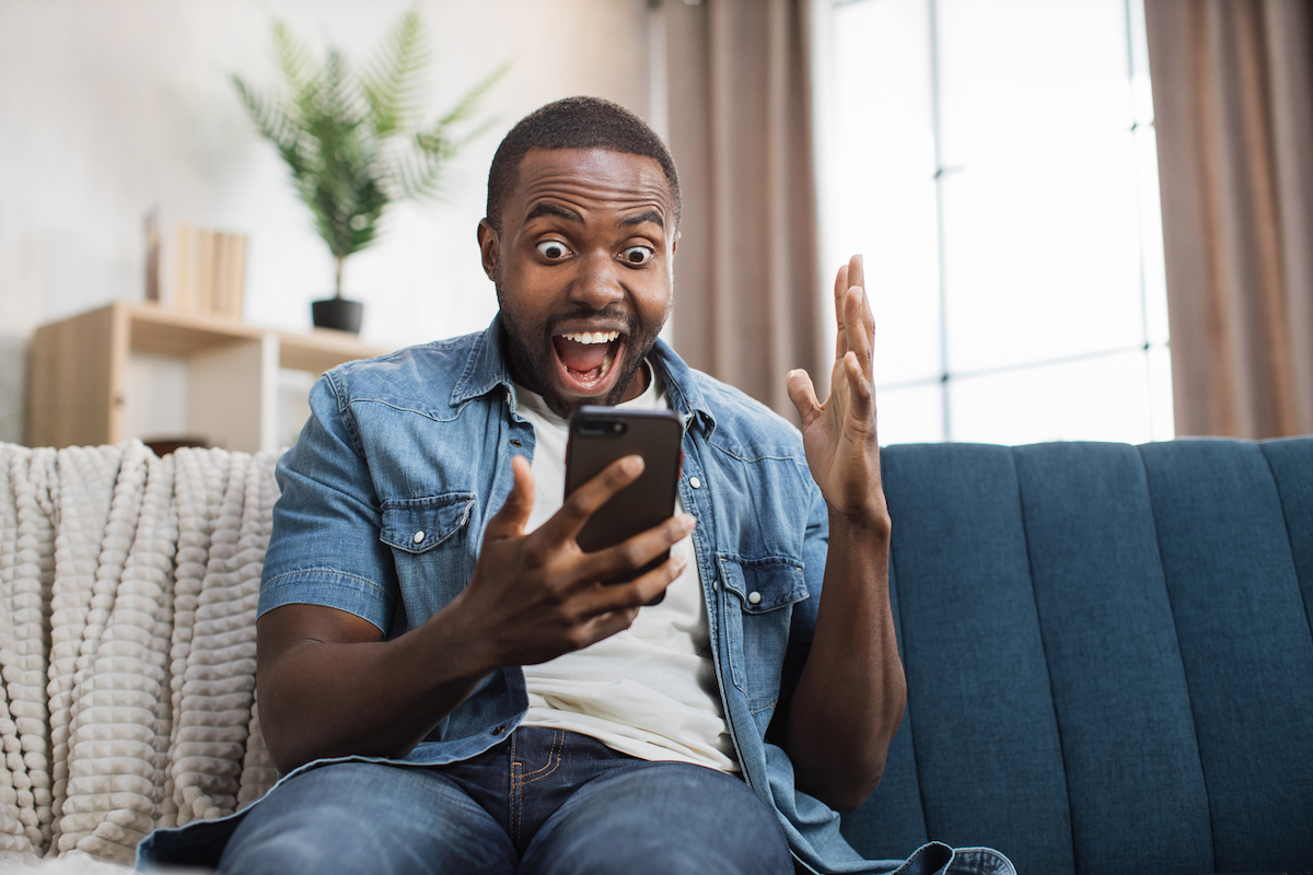 Overjoyed man celebrating success with yes gesture while getting some goods news on mobile phone.