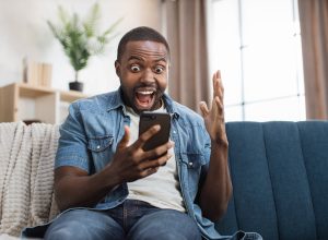 Overjoyed man celebrating success with yes gesture while getting some goods news on mobile phone.