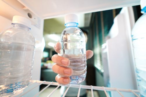 Person grabbing a water bottle from their fridge. 