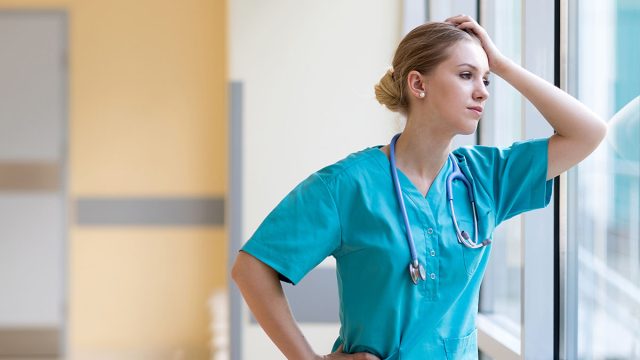 Tired,Female,Nurse,In,Hospital,Corridor