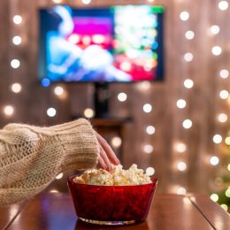 Woman eating popcorn watching Christmas movies.