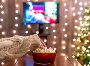 Woman eating popcorn watching Christmas movies.