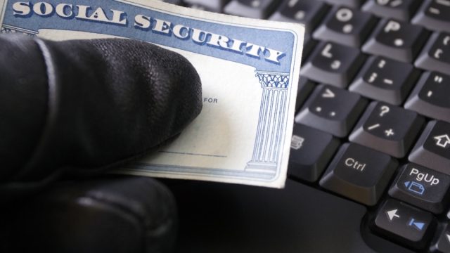 identity theft gloved hand holding social security card