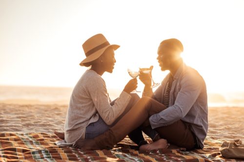 Man and woman toasting with wine glasses on the beach