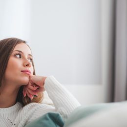 Woman in a white sweater, looking out the window being intuitive.