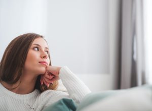 Woman in a white sweater, looking out the window being intuitive.