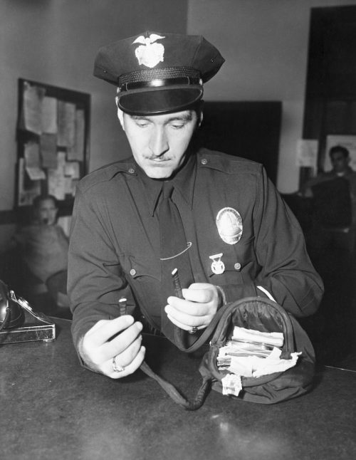 Police officer Howard Rose examining the found purse of Jean Spangler circa 1949