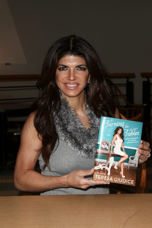 Teresa Giudice posing with her book "Turning the Tables: From Housewife to Inmate and Back Again" in 2016