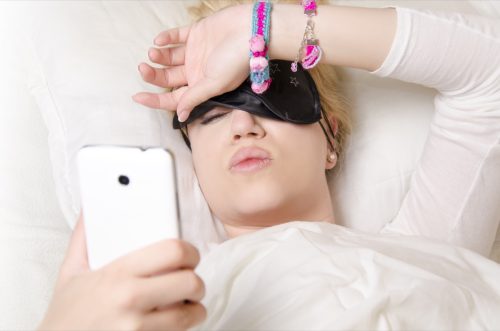 Woman lying in bed with her phone. 