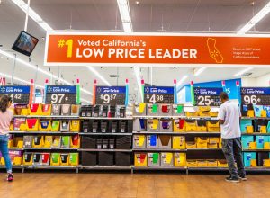 People shopping for back to school items in one of the Walmart stores; Banner advertising the low price leader status in California displayed above