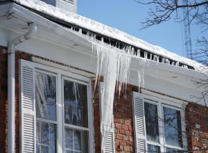 Icicles causing a house's gutters to sag in winter.