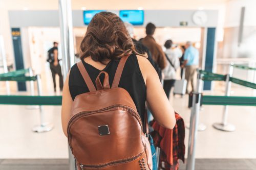 A woman wearing a backpack while waiting to go through airport security