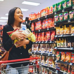 Young woman in a grocery store, carrying snacks in her hands.