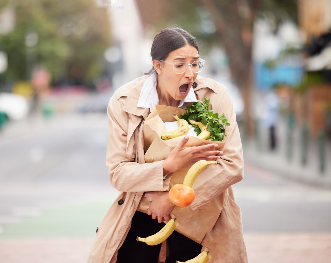 Young woman trying to catch her groceries after her bag broke.