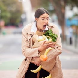 Young woman trying to catch her groceries after her bag broke.