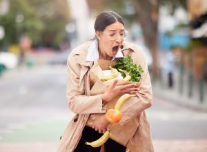 Young woman trying to catch her groceries after her bag broke.