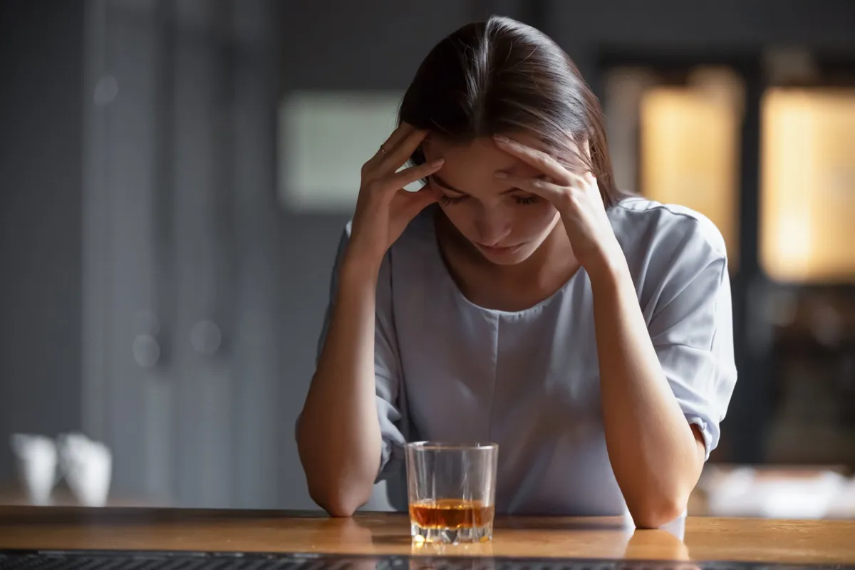 Woman looks upset struggling with alcoholism.