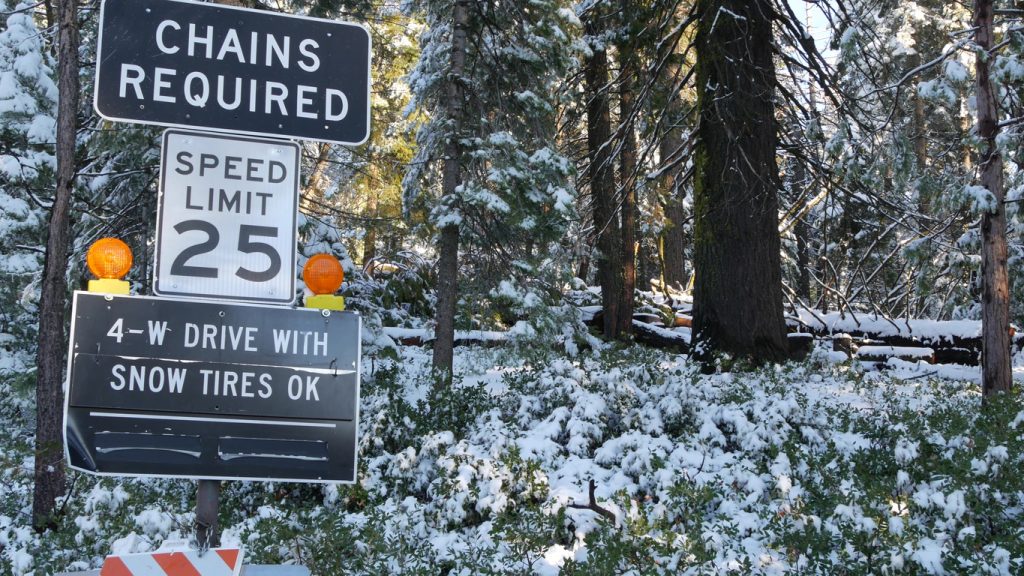Signs that read "chains required" and a 25 mile per hour speed limit in Yosemite National Park, a bottom sign that says "four wheel drive with snow tires OK"