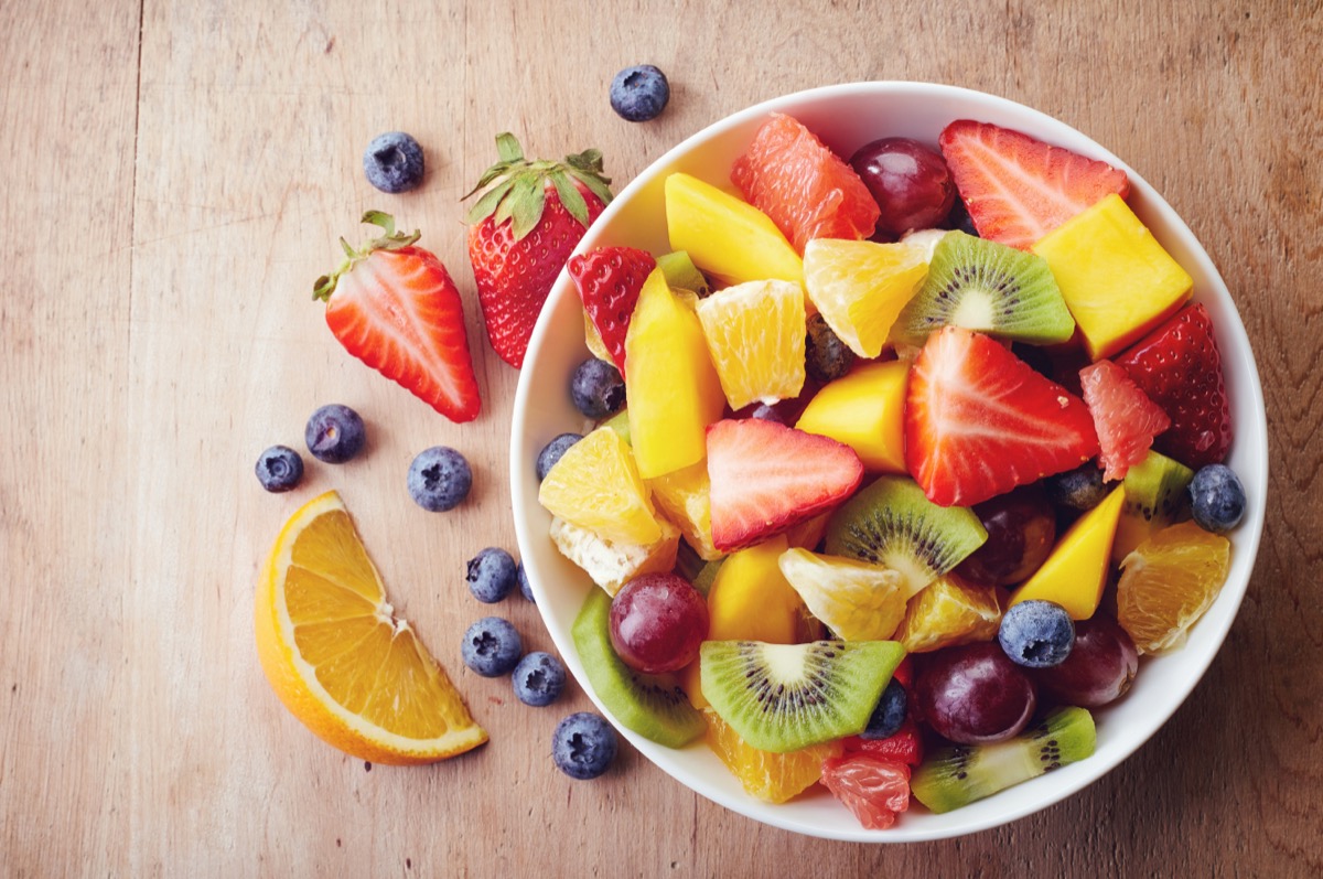 A bowl of fruit with oranges, strawberries and blueberries.
